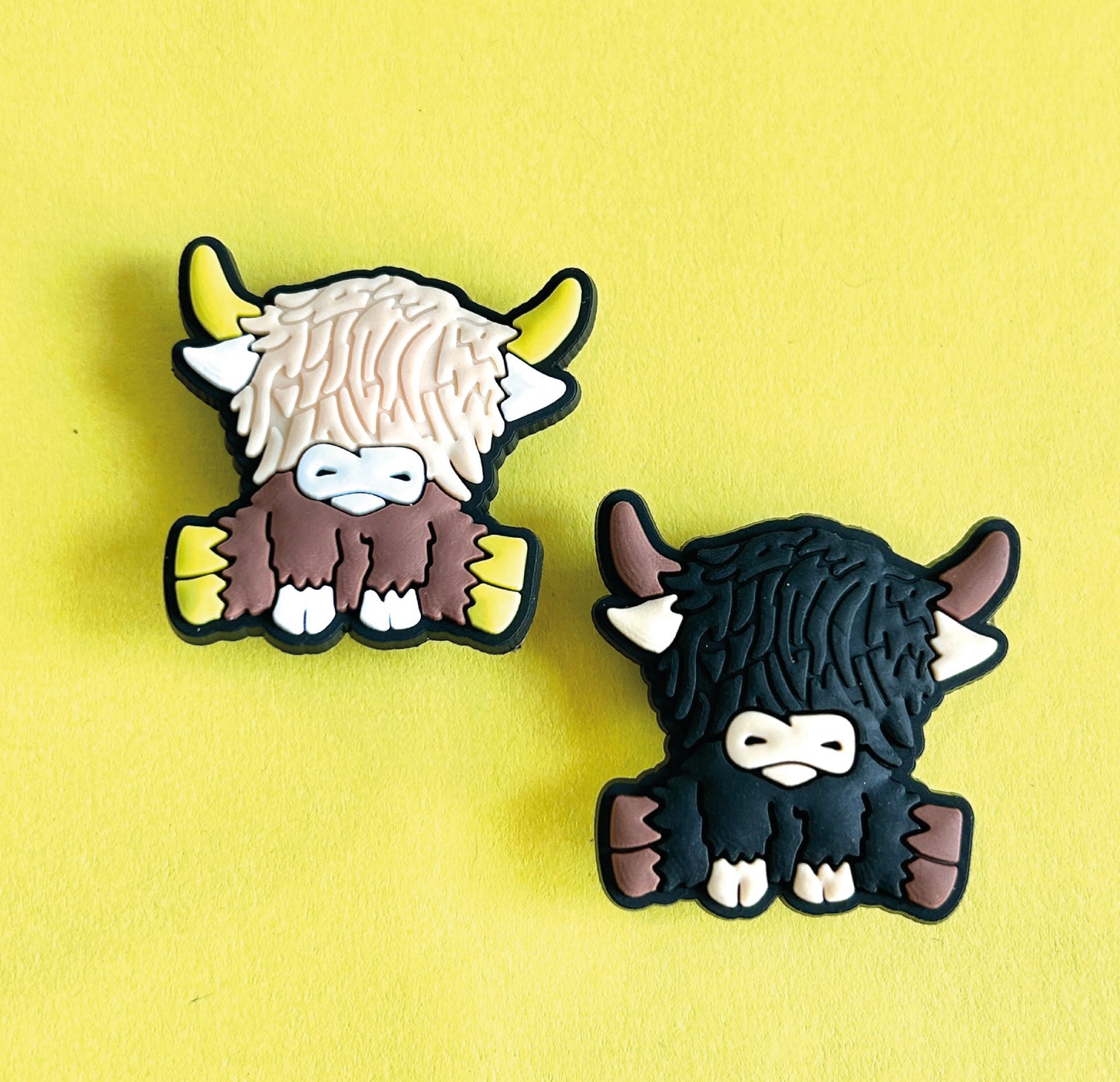 Two highland cows, one black one brown. Croc shoe charm gibbets.