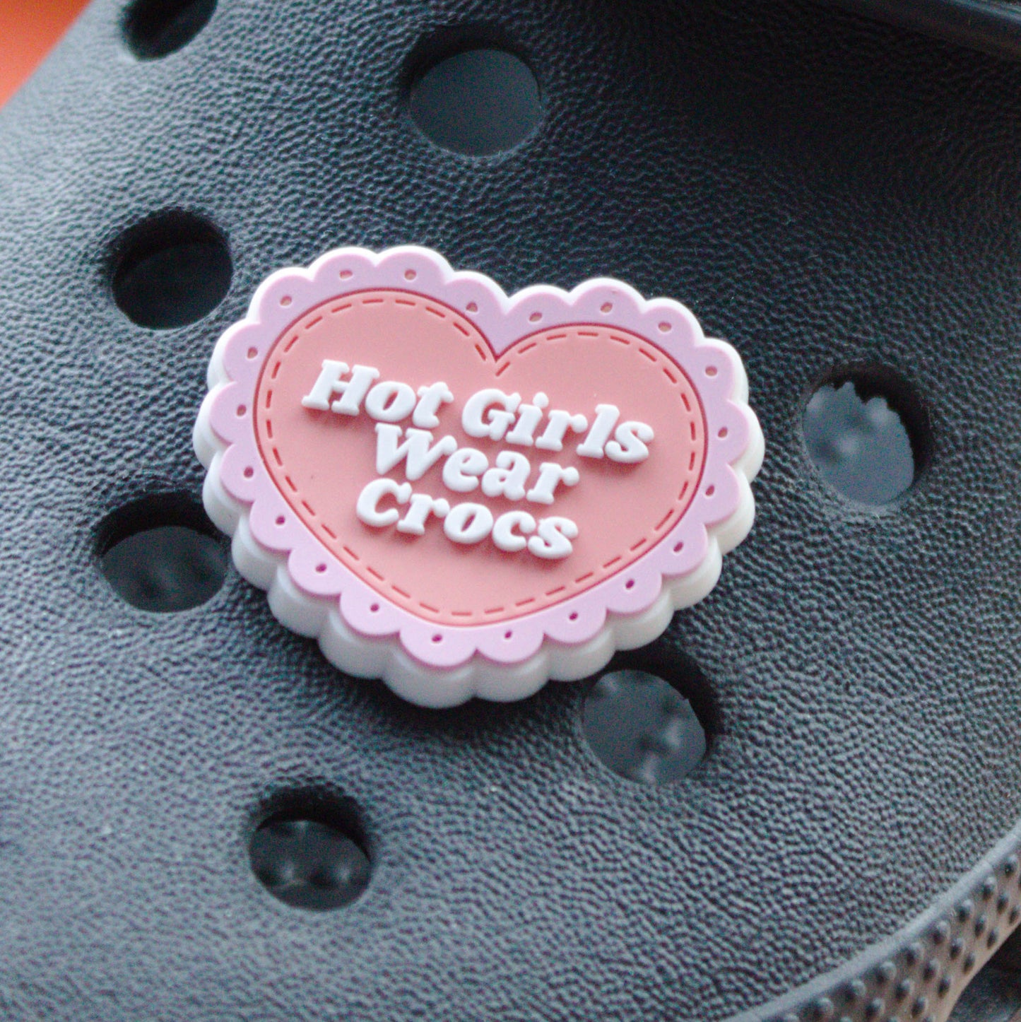 Hot girls wear crocs pink shoe charm. Scalloped around the edge. Rubber material. Modelled on a black croc shoe.