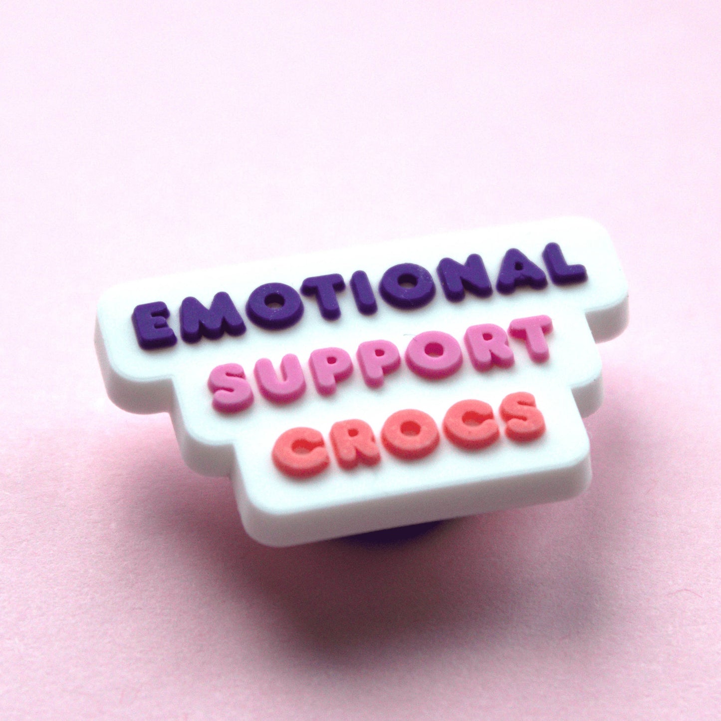 Emotional Support Crocs Slogan croc like shoe charm. White, pink and purple. Close up image.