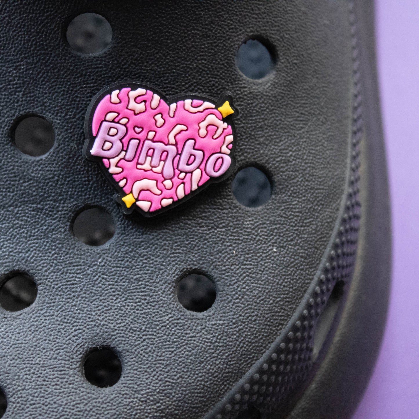 Bimbo word inside a pink leopard print heart. Modelled on a black croc shoe.