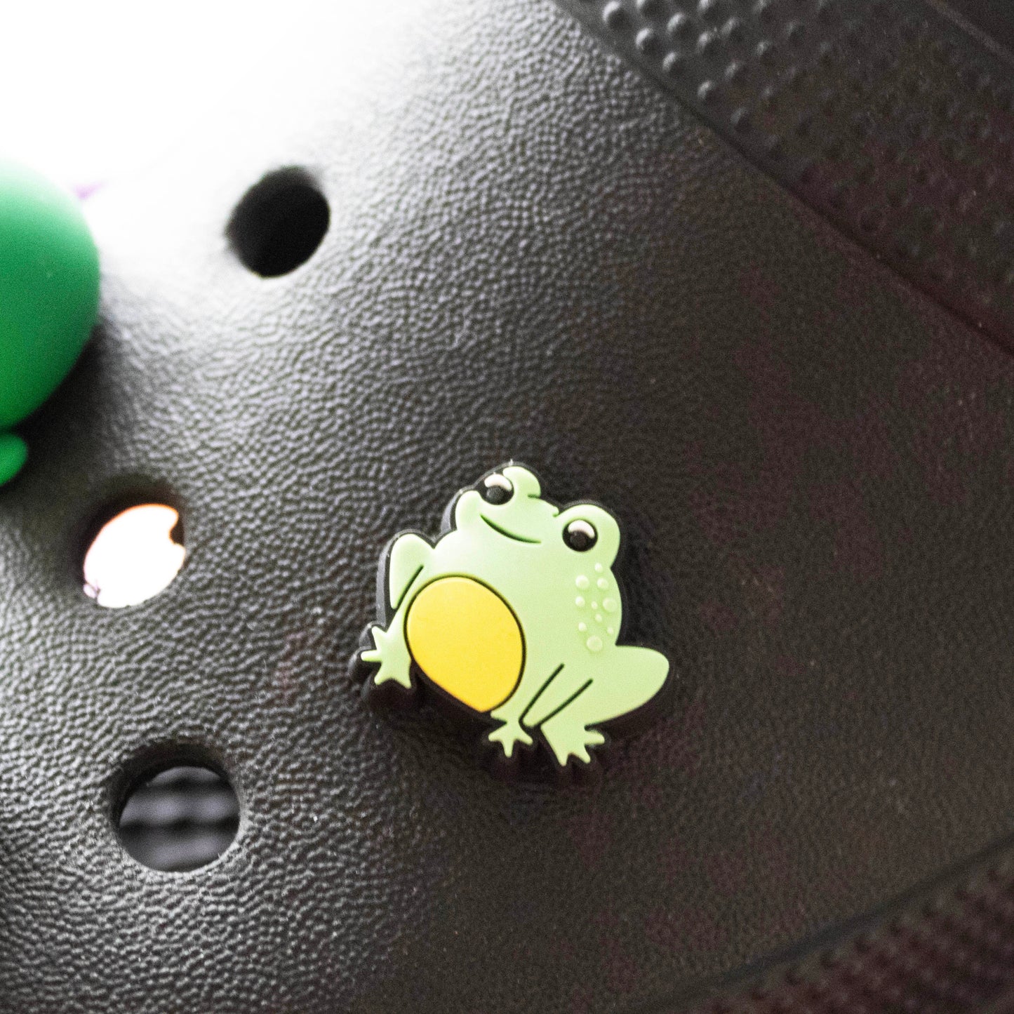 Green small frog croc like shoe charm. Shown on a black croc charm.