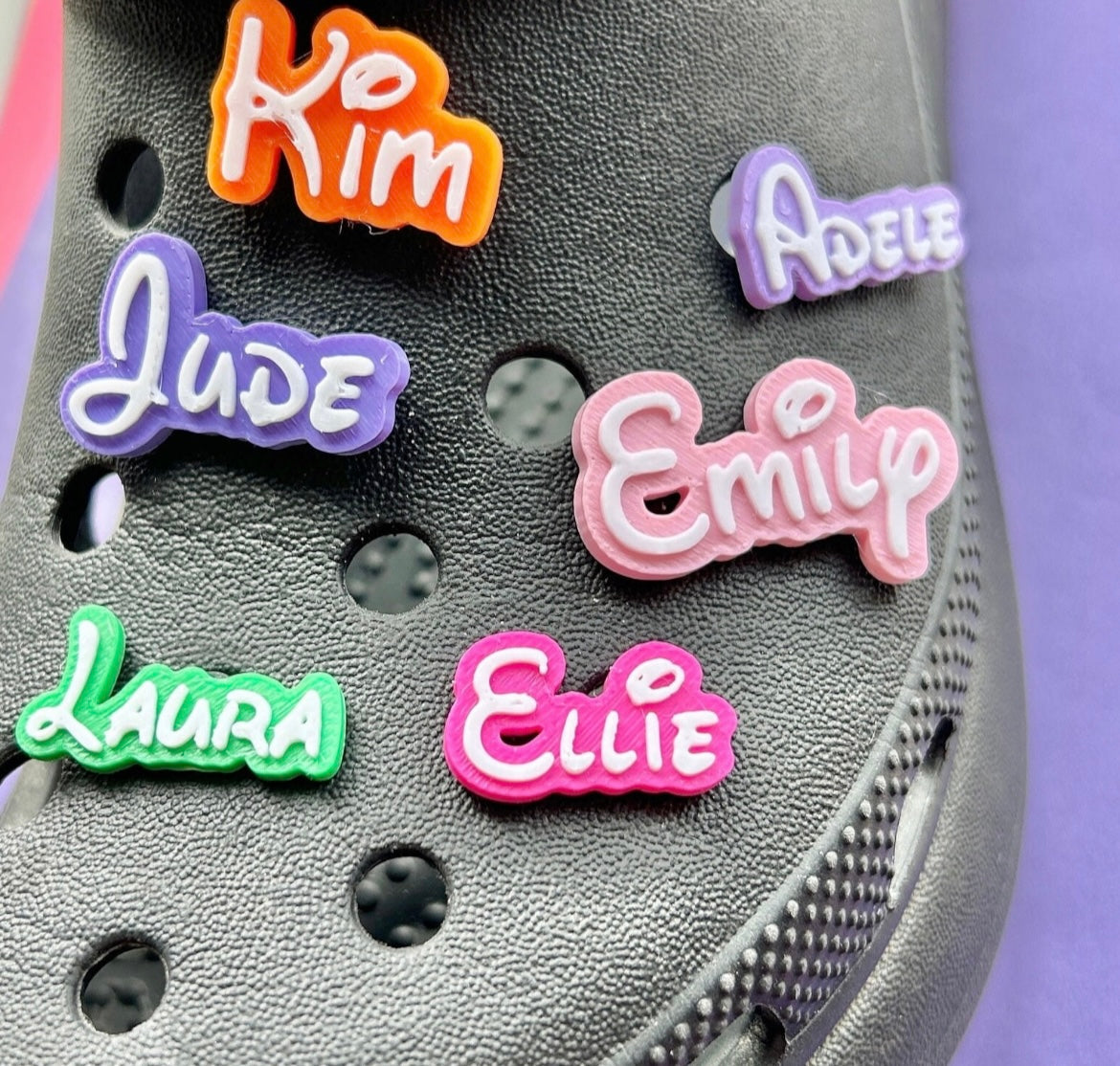 3D Printed personalised croc Name charms. Examples shown on a black croc shoe.