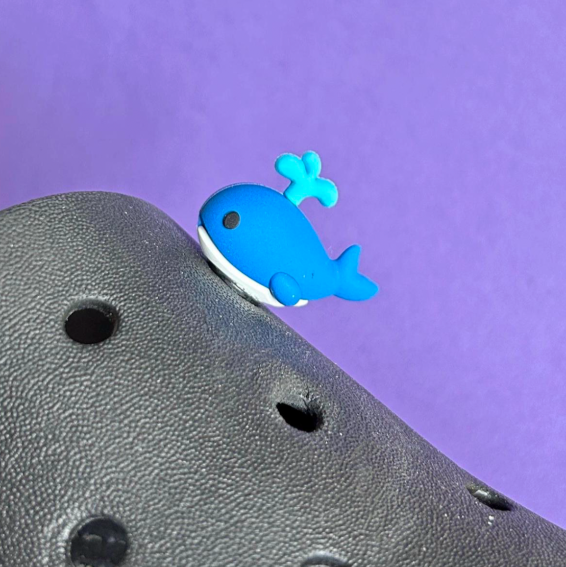 3D Whale croc like shoe charm squirting water. Shown on a black croc shoe.