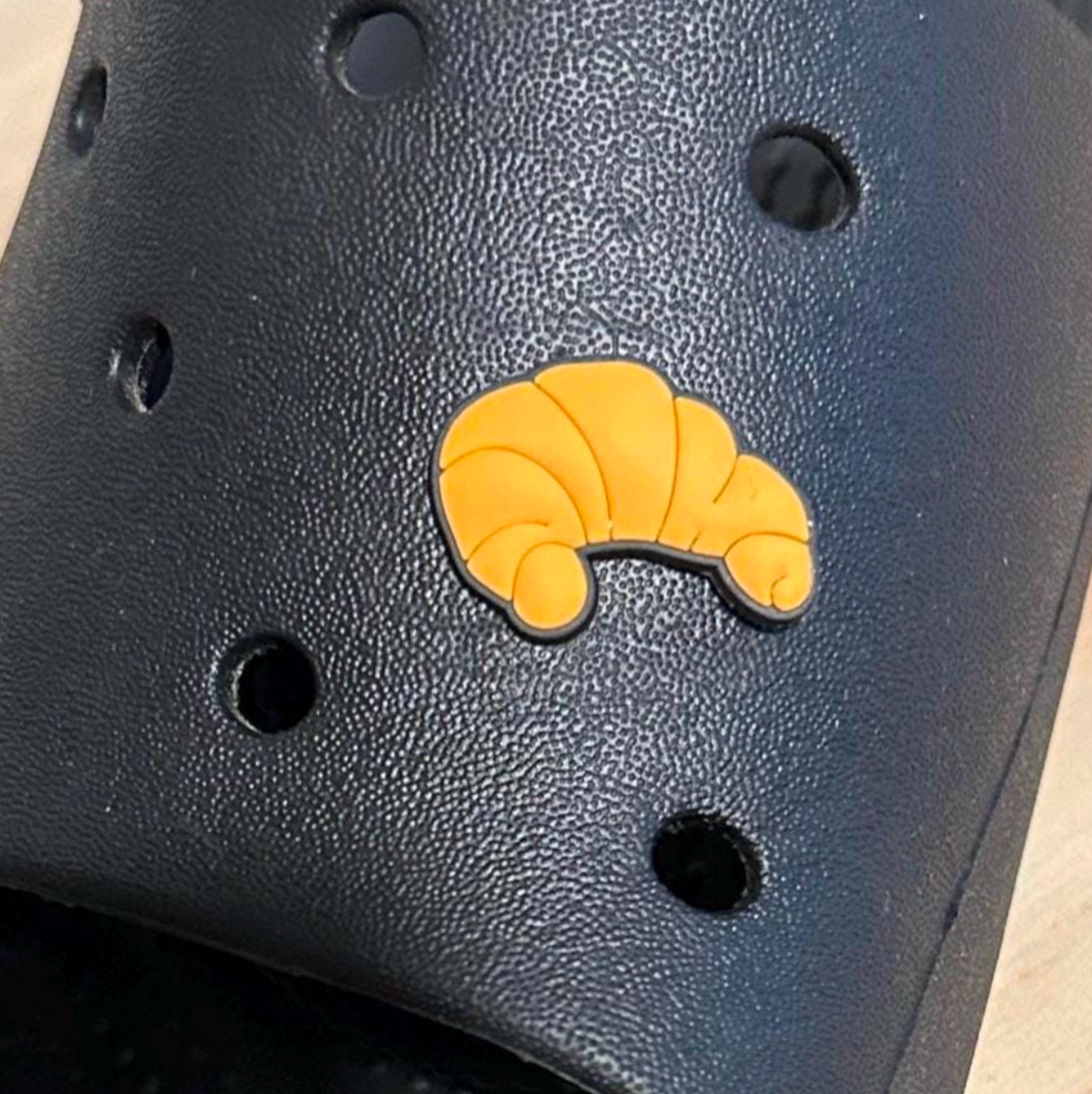 Croissant croc like shoe charm. Shown on a black croc shoe.