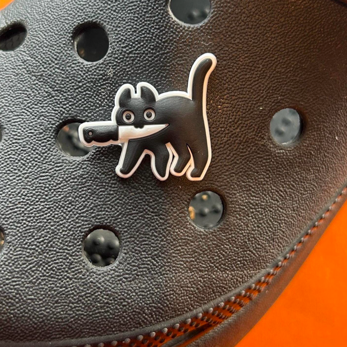 Black and white murder cat croc like shoe charm. Shown on a black croc shoe.