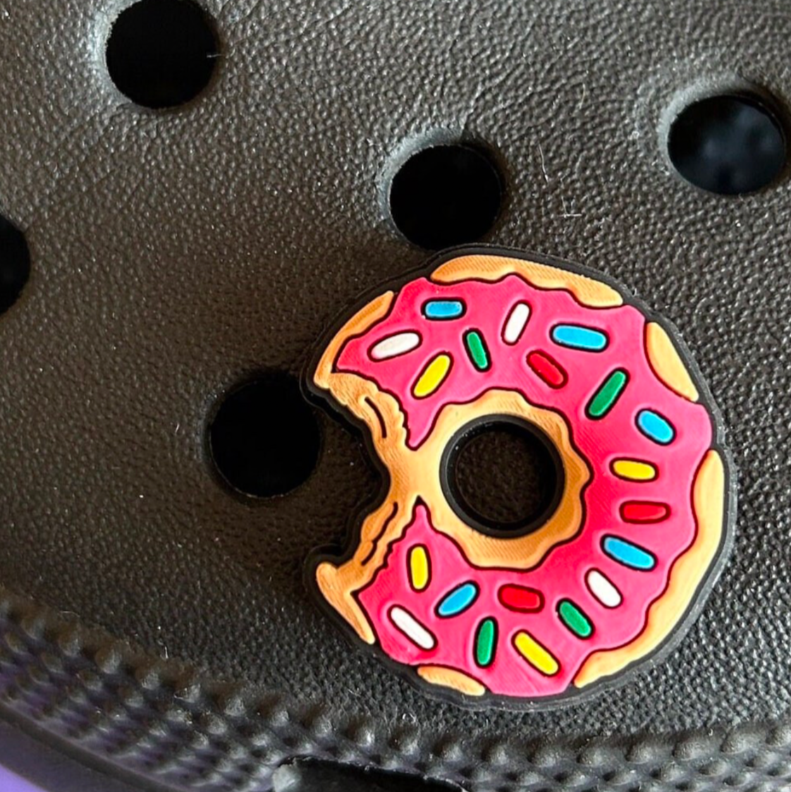 Pink Iced Doughnut croc like shoe charm. Shown on a black croc shoe.