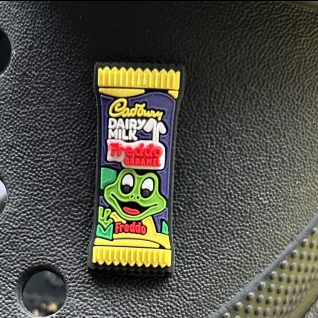 Fred Frog Caramel Bar croc like shoe charm. Shown on a black croc shoe.