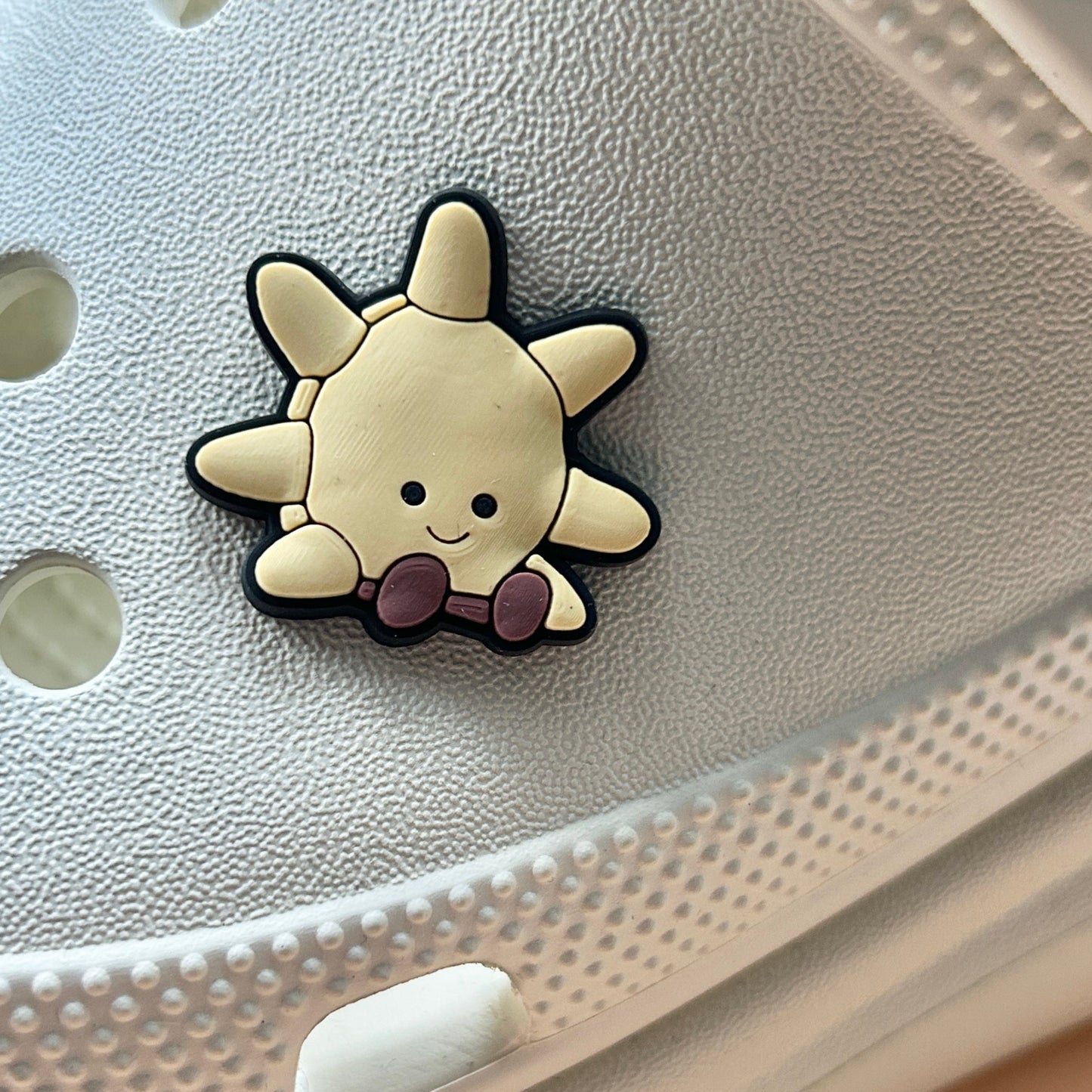 Sun croc like shoe charm. Shown on a cream croc shoe.