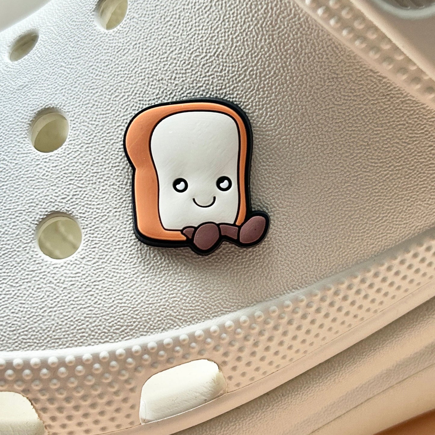 Happy Toast croc like shoe charm. Shown on a cream croc shoe.