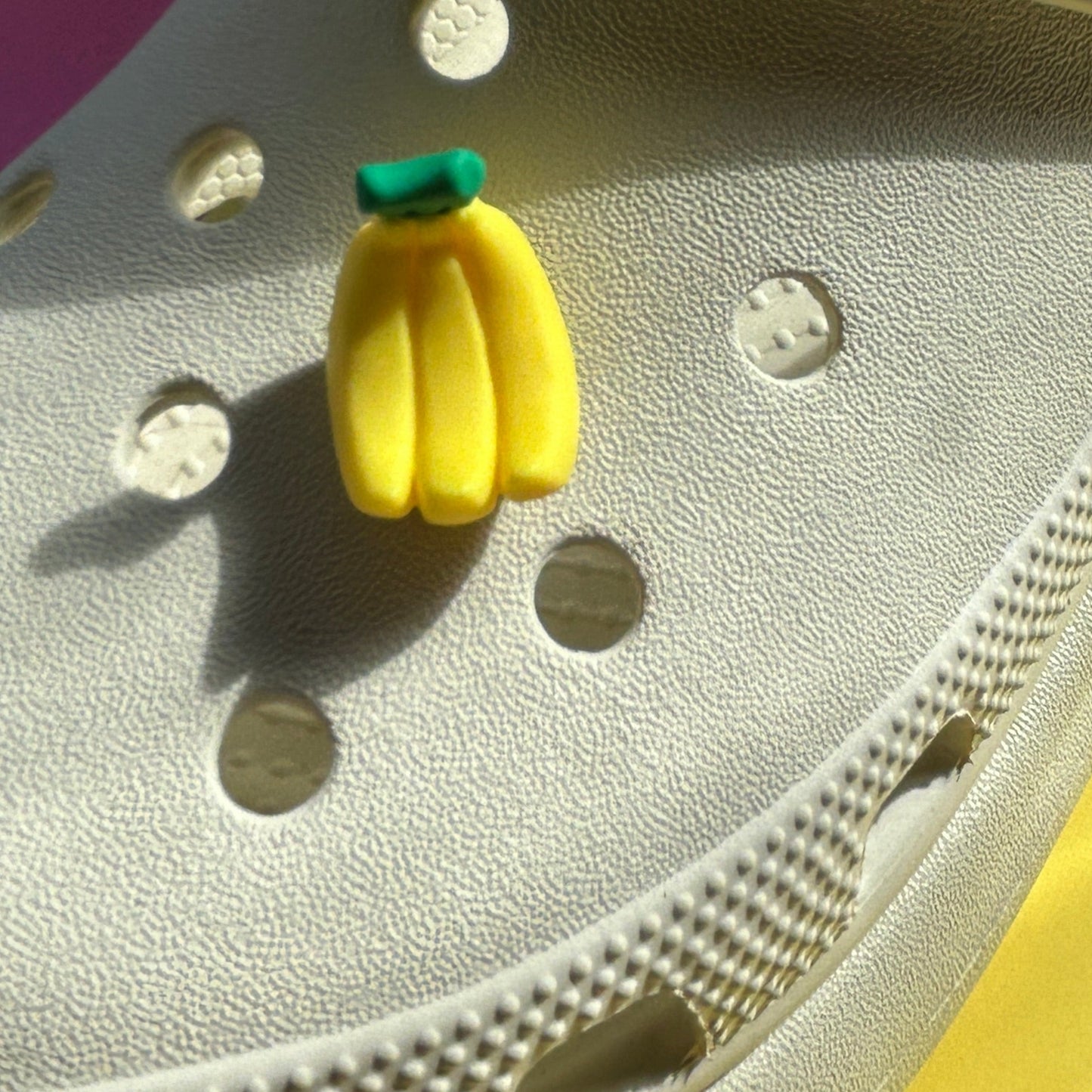 3D bunch of bananas croc shoe charm. Yellow and green stalk. Modelled on a cream croc shoe from the side.