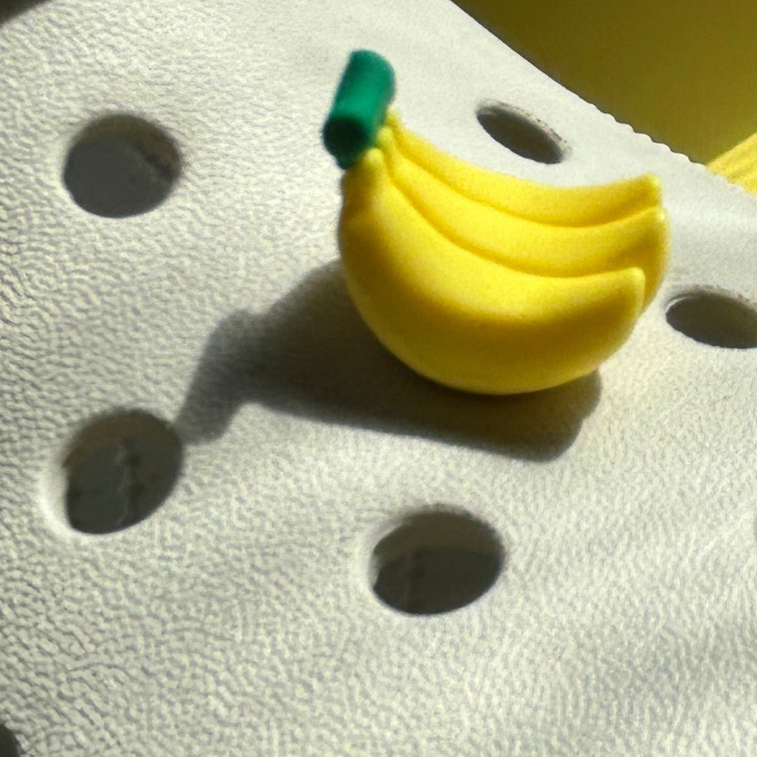 3D bunch of bananas croc shoe charm. Yellow and green stalk. Modelled on a cream croc shoe from the front.