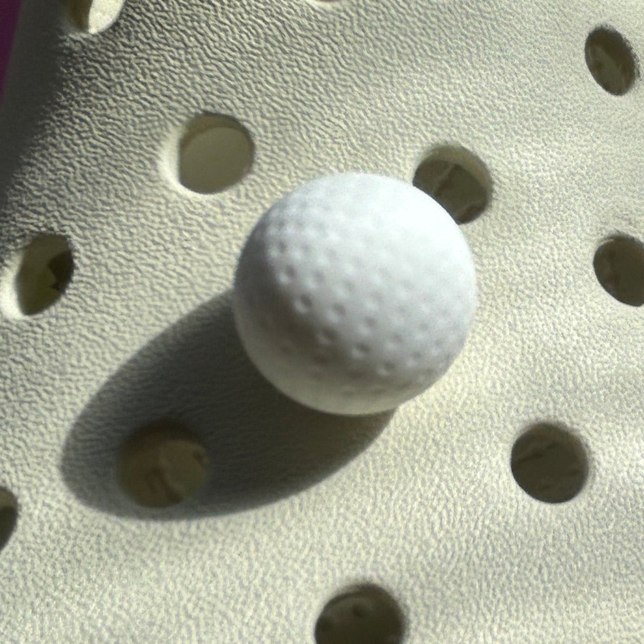 3D Golf Ball Croc shoe charm. White modelled on a cream croc shoe.