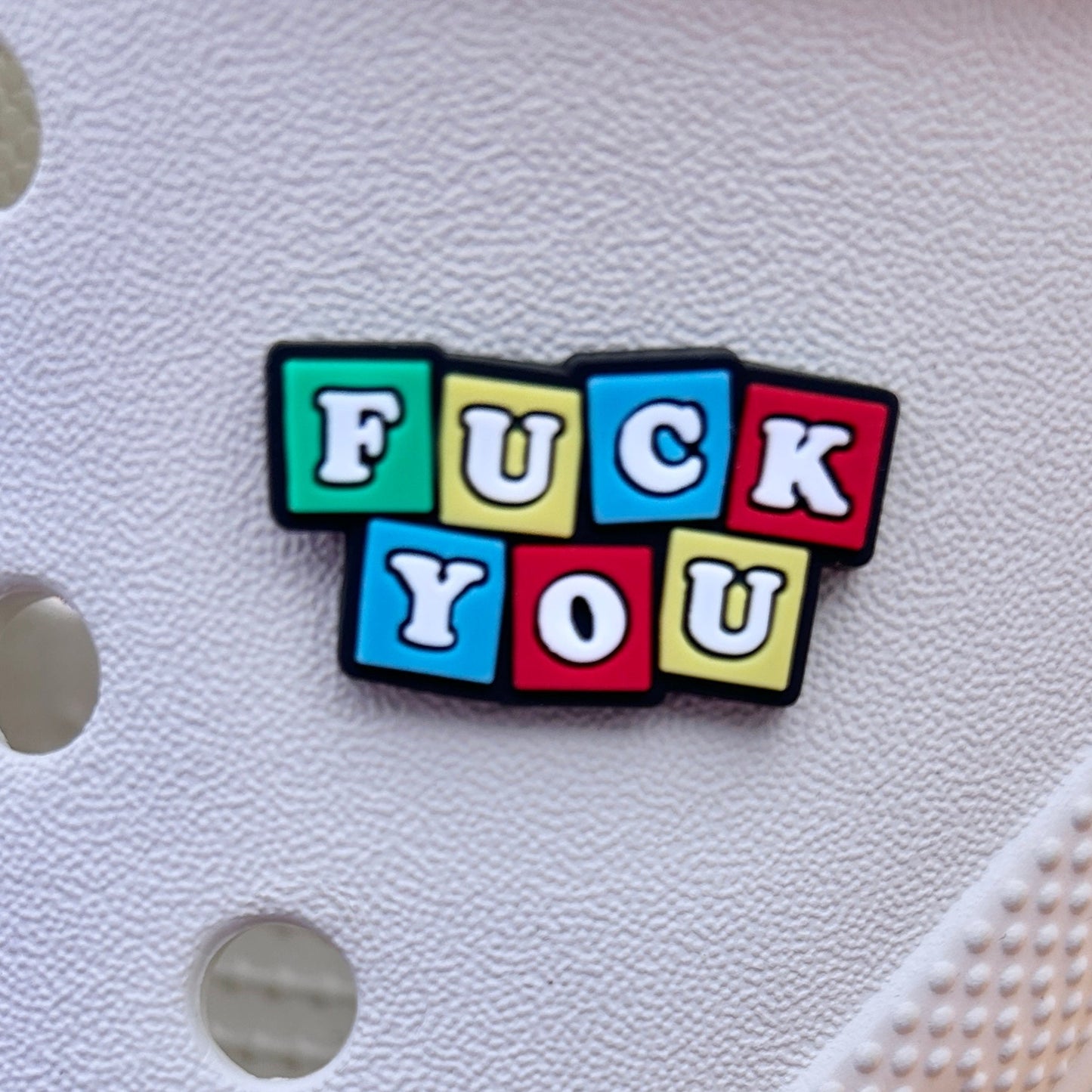 Multicoloured Fuck You Toy bricks croc like shoe charm. Shown on a cream croc shoe.
