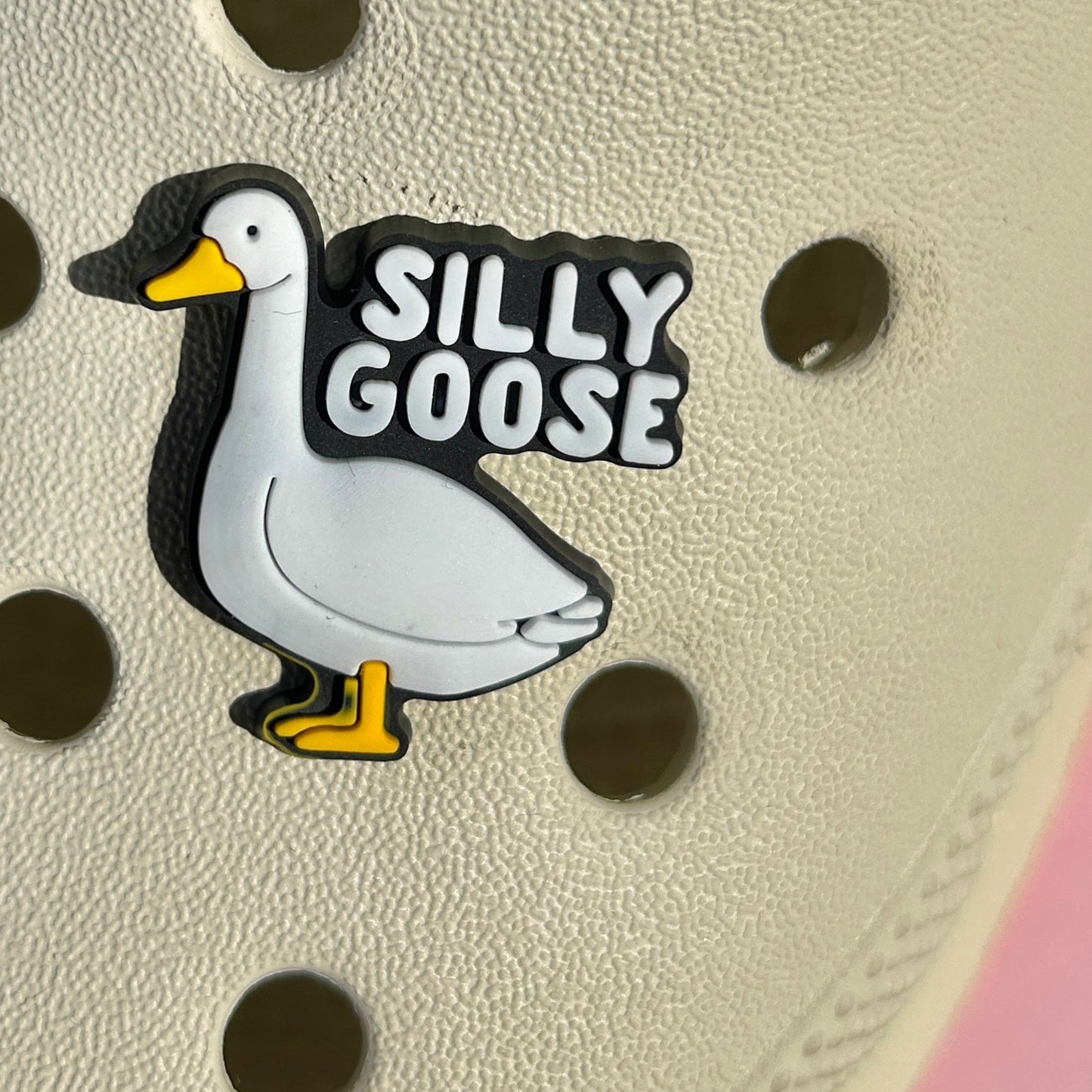 Silly goose croc like shoe charm shown on a cream croc shoe.