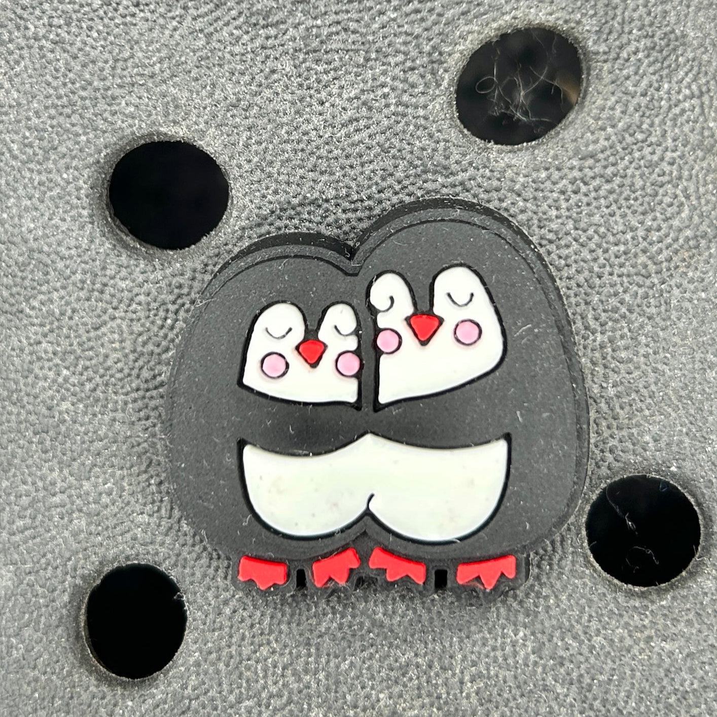 Black and White cute cuddling Penguins croc shoe charm. Shown on a black croc shoe.