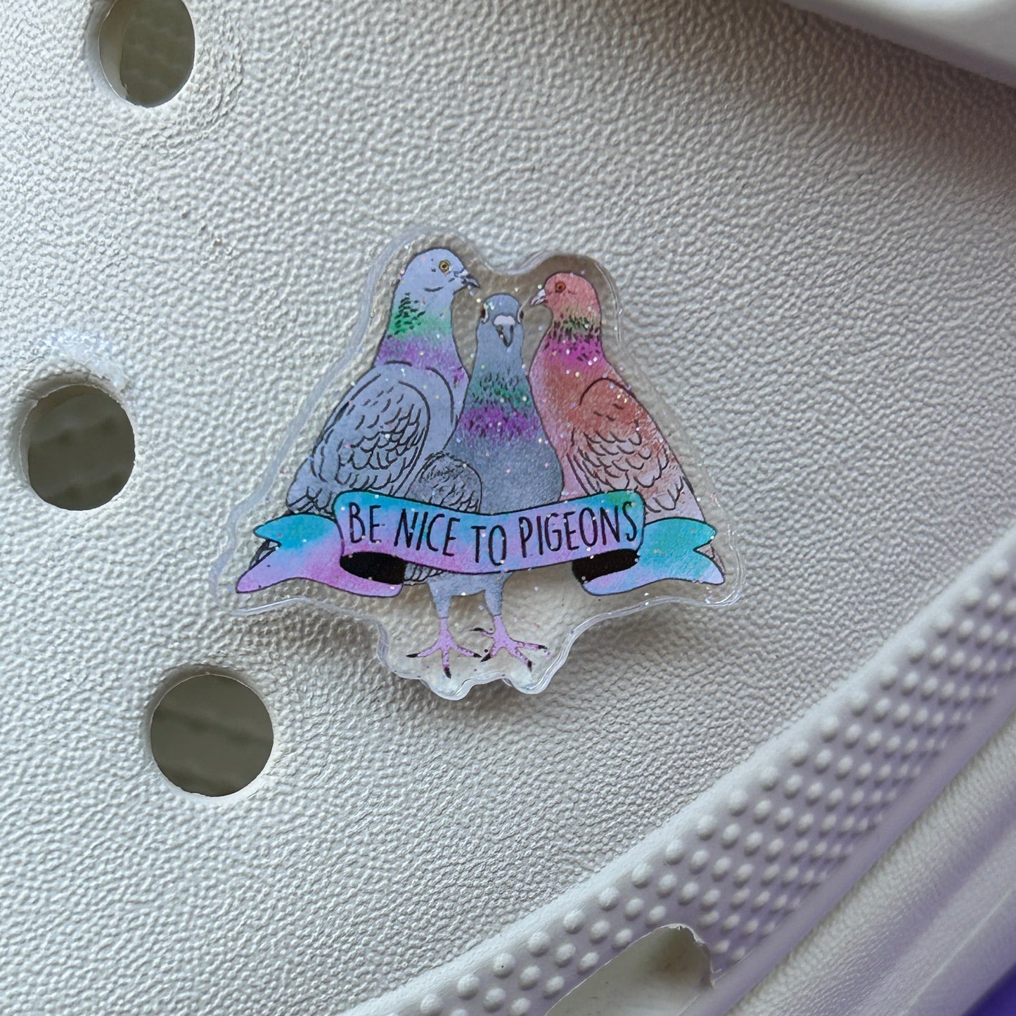 Sparkly pigeon slogan shoe charm on white clog.