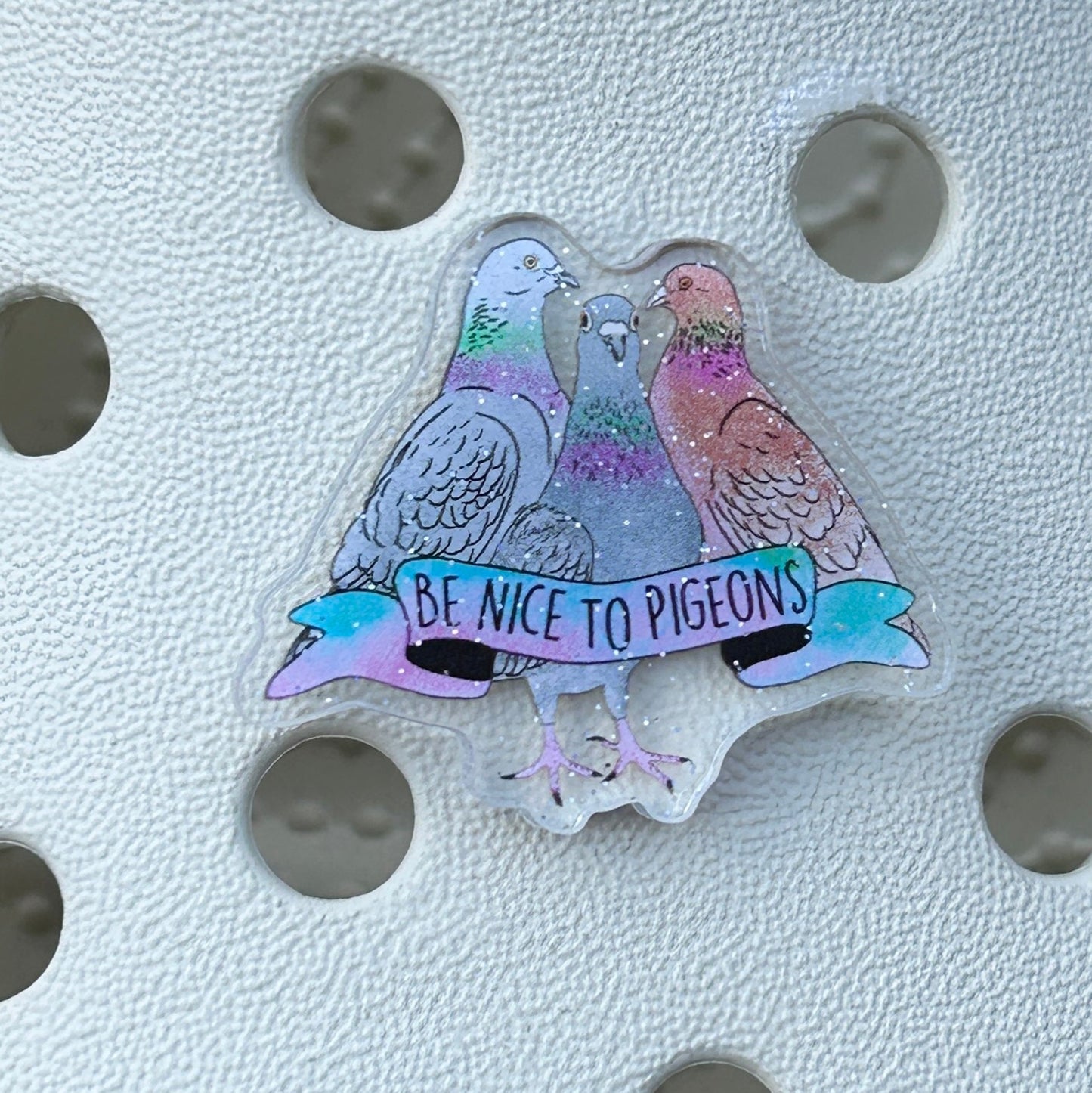Sparkly pigeon slogan shoe charm on white clog.