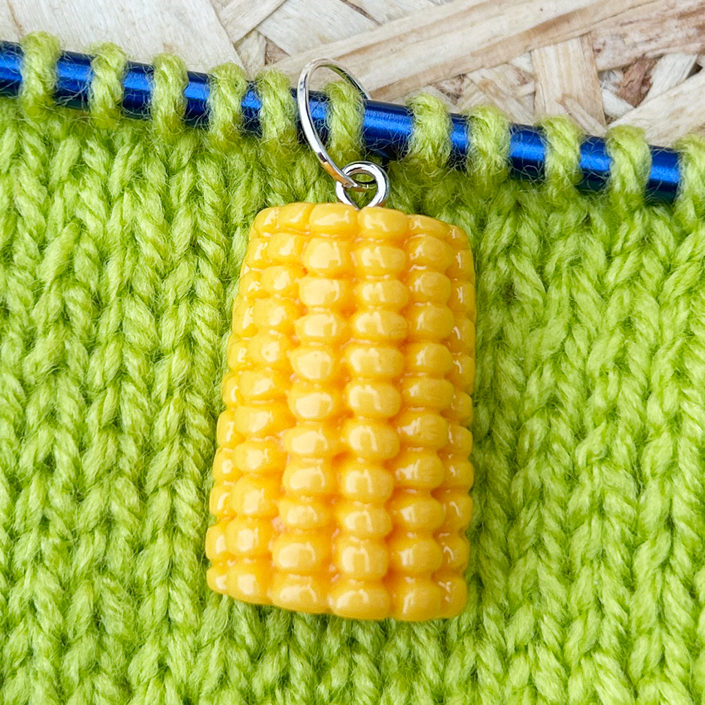 Corn knitting stitch marker on a green knitted background