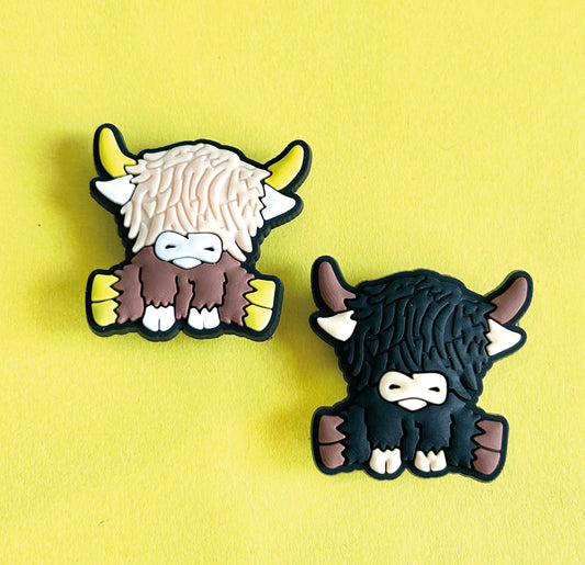 Two highland cows, one black one brown. Croc shoe charm gibbets. 
