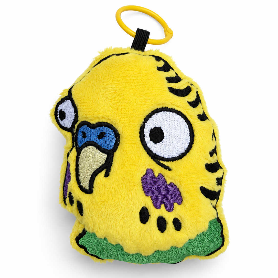 A yellow plush bird-shaped keychain or bag charm with embroidered facial features, black tiger-like stripes, a blue beak, purple chest detail, green underbelly, and a yellow ring at the top, shown on a white background.