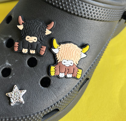 Two highland cows, one black one brown. Croc shoe charm gibbets. 