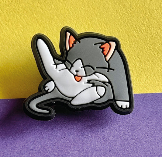 Grey and white cat licking croc shoe charm. 
