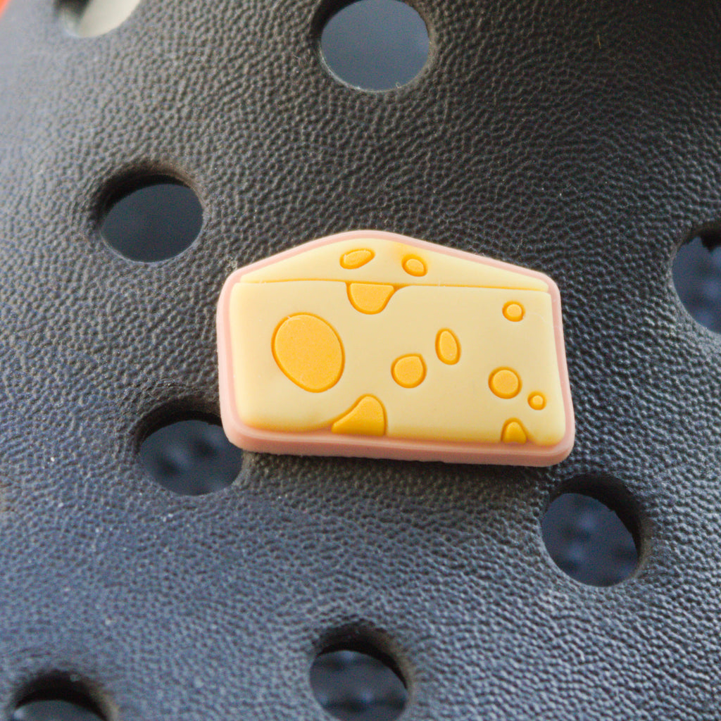 Yellow wedge of cheese croc like shoe charm. Shown on a black croc shoe. 