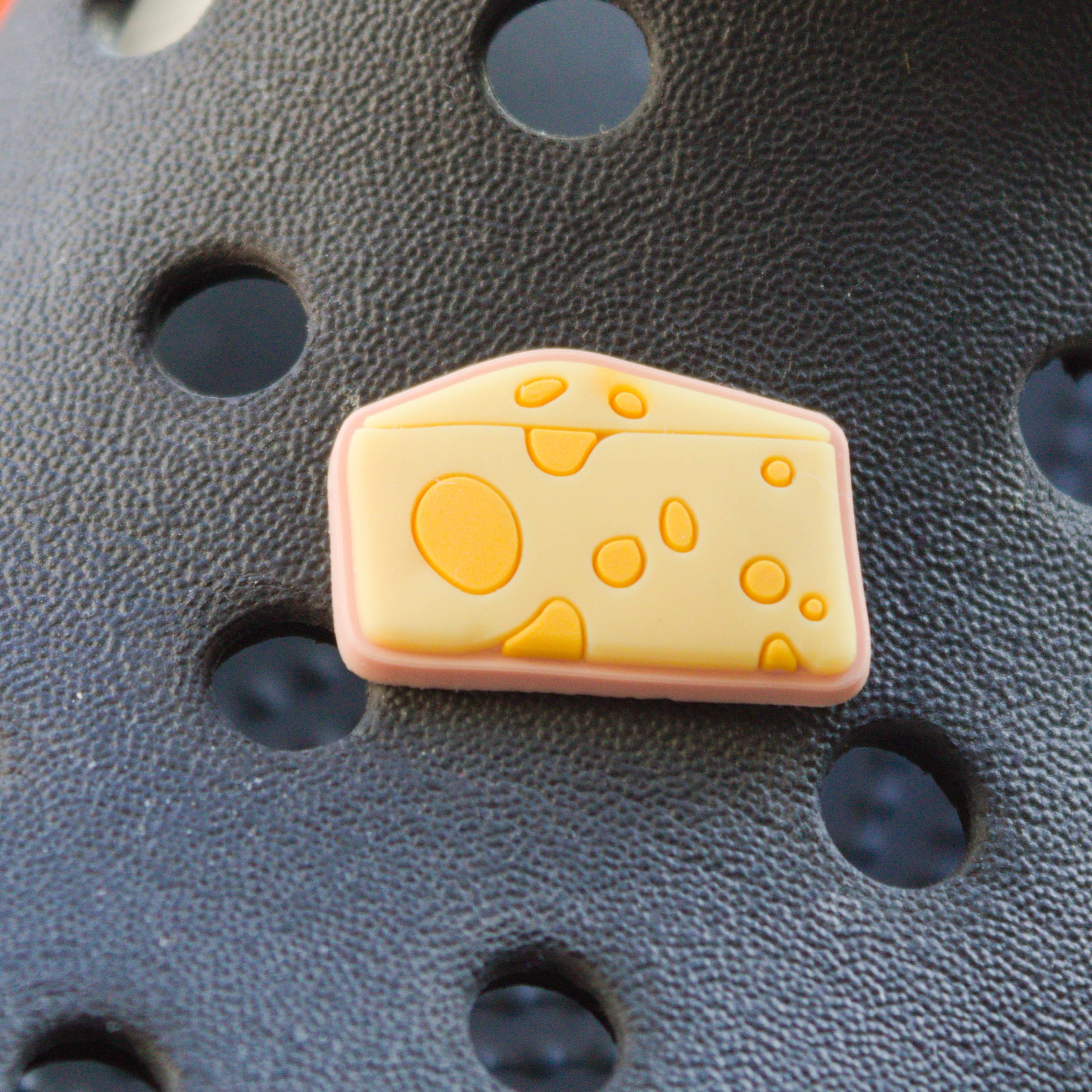 Yellow wedge of cheese croc like shoe charm. Shown on a black croc shoe. 
