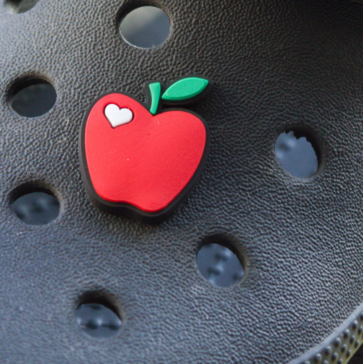 Red Apple croc like shoe charm with white heart accent. Modelled on a black croc shoe.