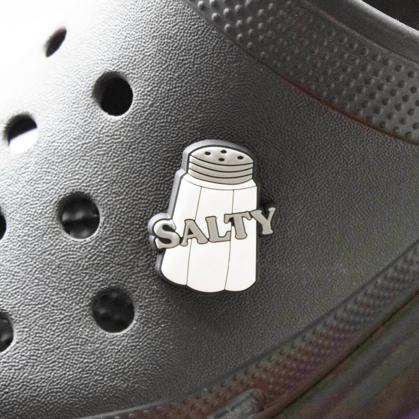 Salty Slogan croc like shoe charm. Barcoded. Shown on a black croc shoe. 