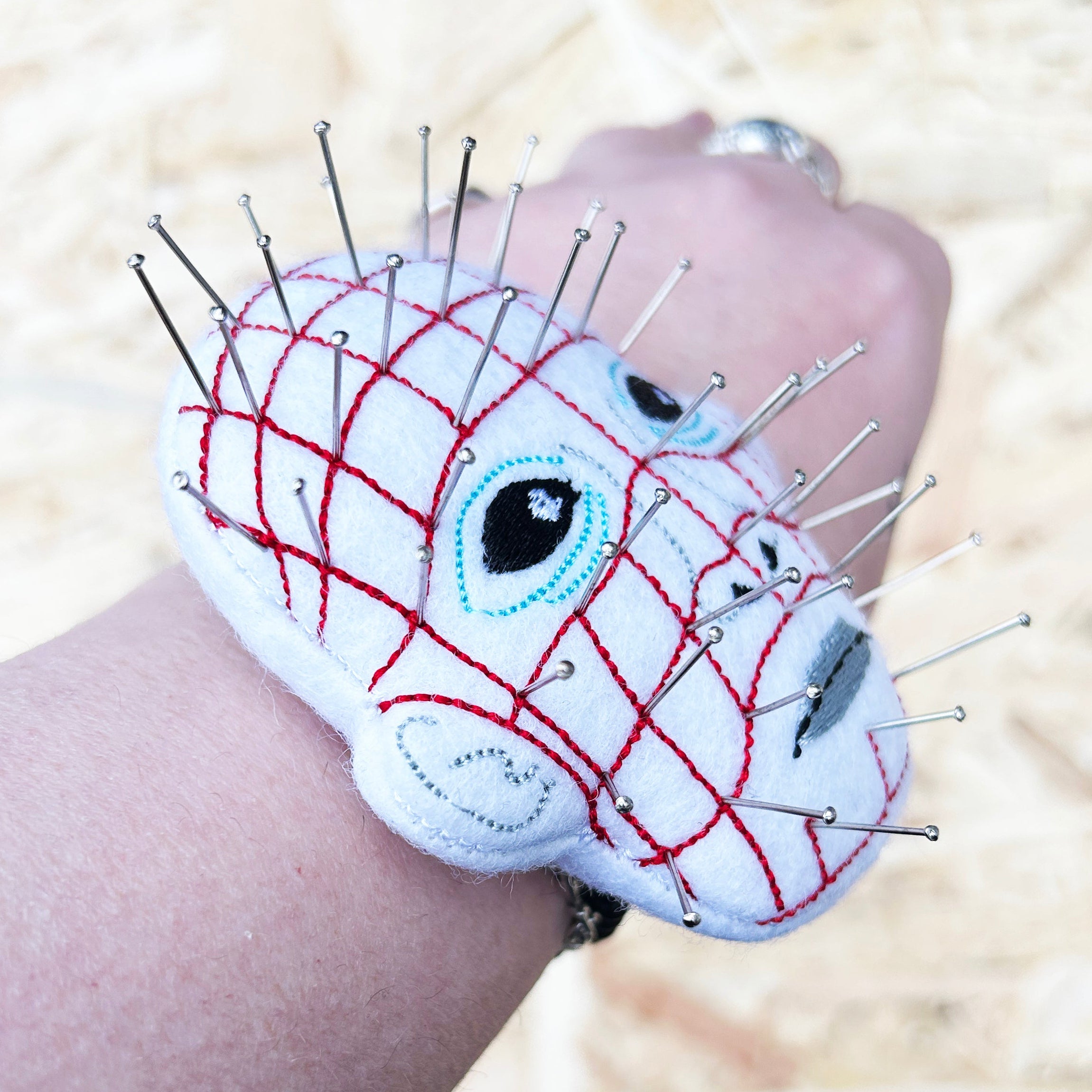 Pin head pincushion, cream modelled on a wrist. 