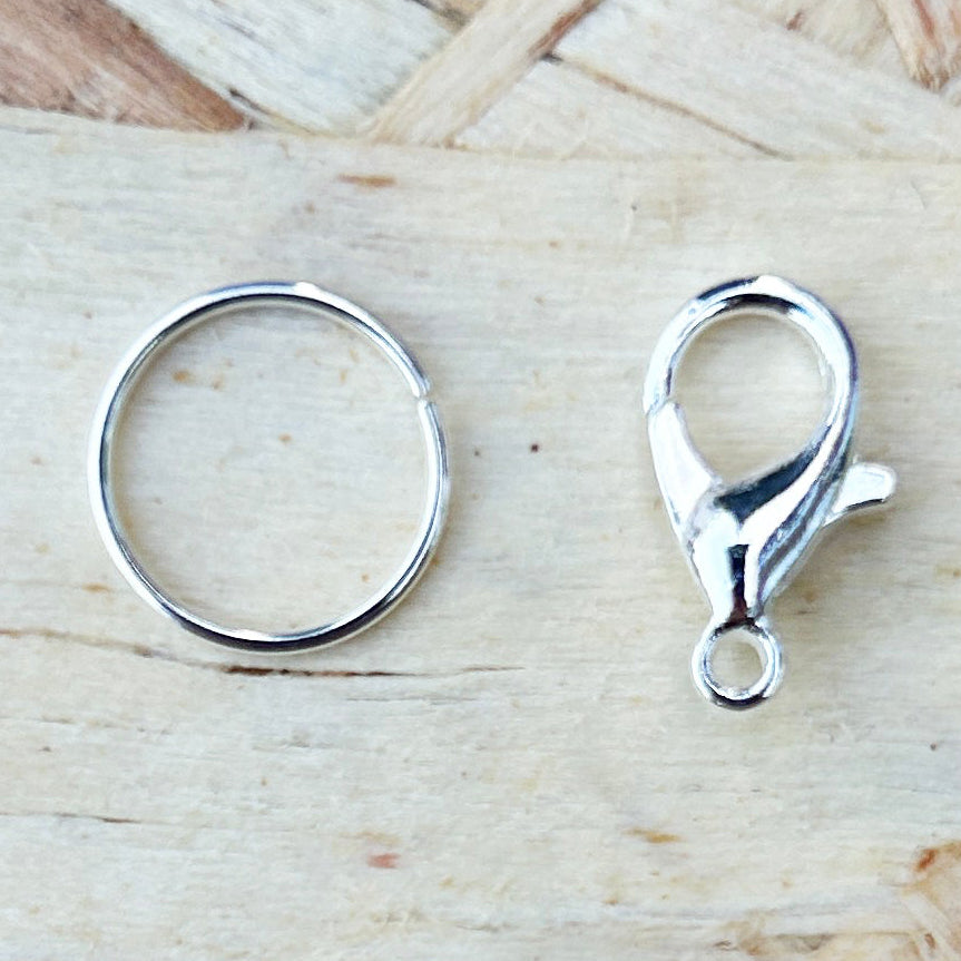 Two silver marker attachments, ring and crab claw on a wooden surface