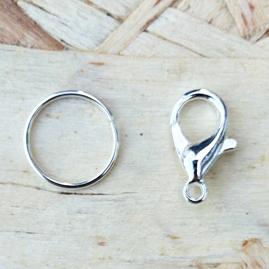 Two silver stitch marker attachments, ring and crabclaw  on a wooden surface