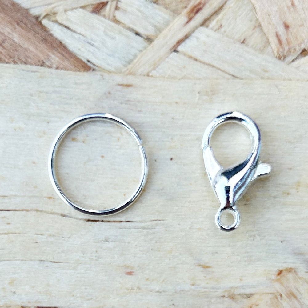 Two silver attachments a ring and a cratbclaw on a wooden surface