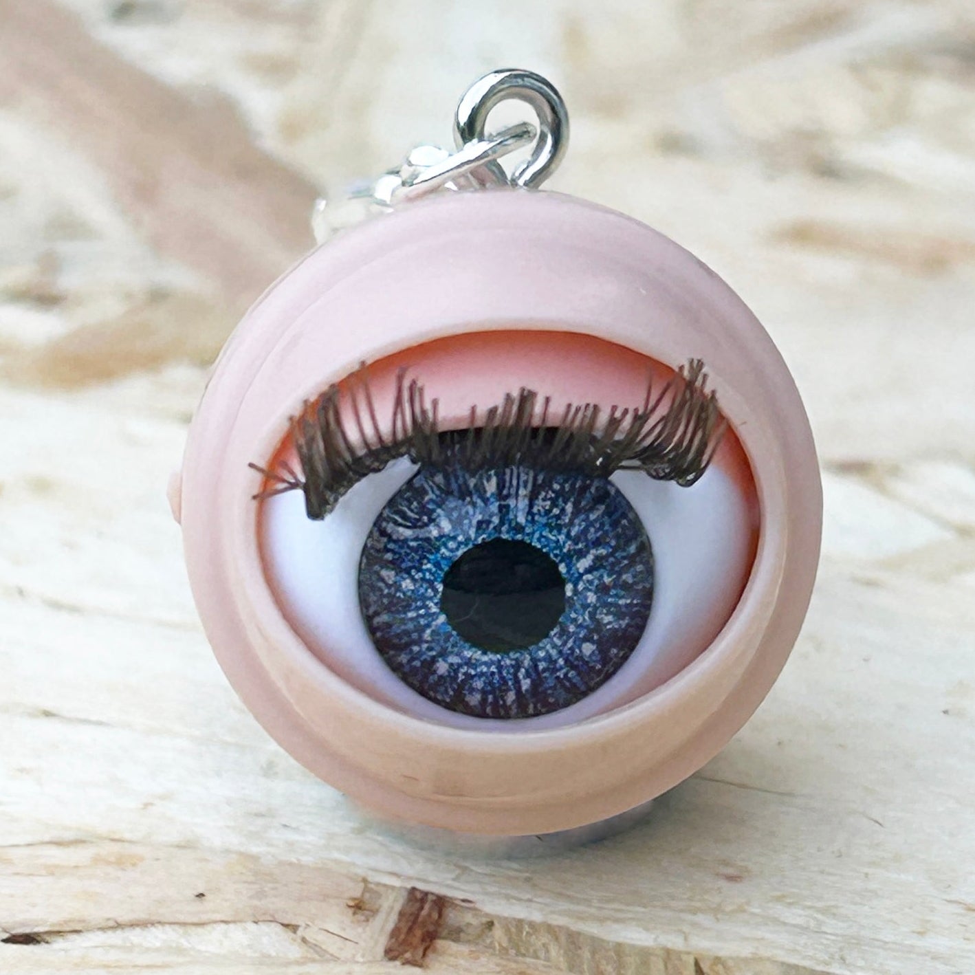 Eyeball-shaped stitch marker on a wooden background