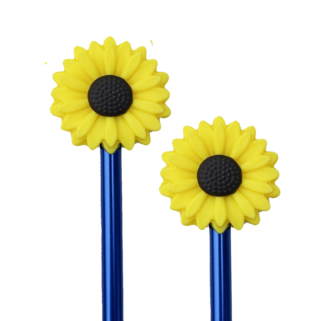 Two blue knitting needles with sunflower point protectors on the ends on a white background