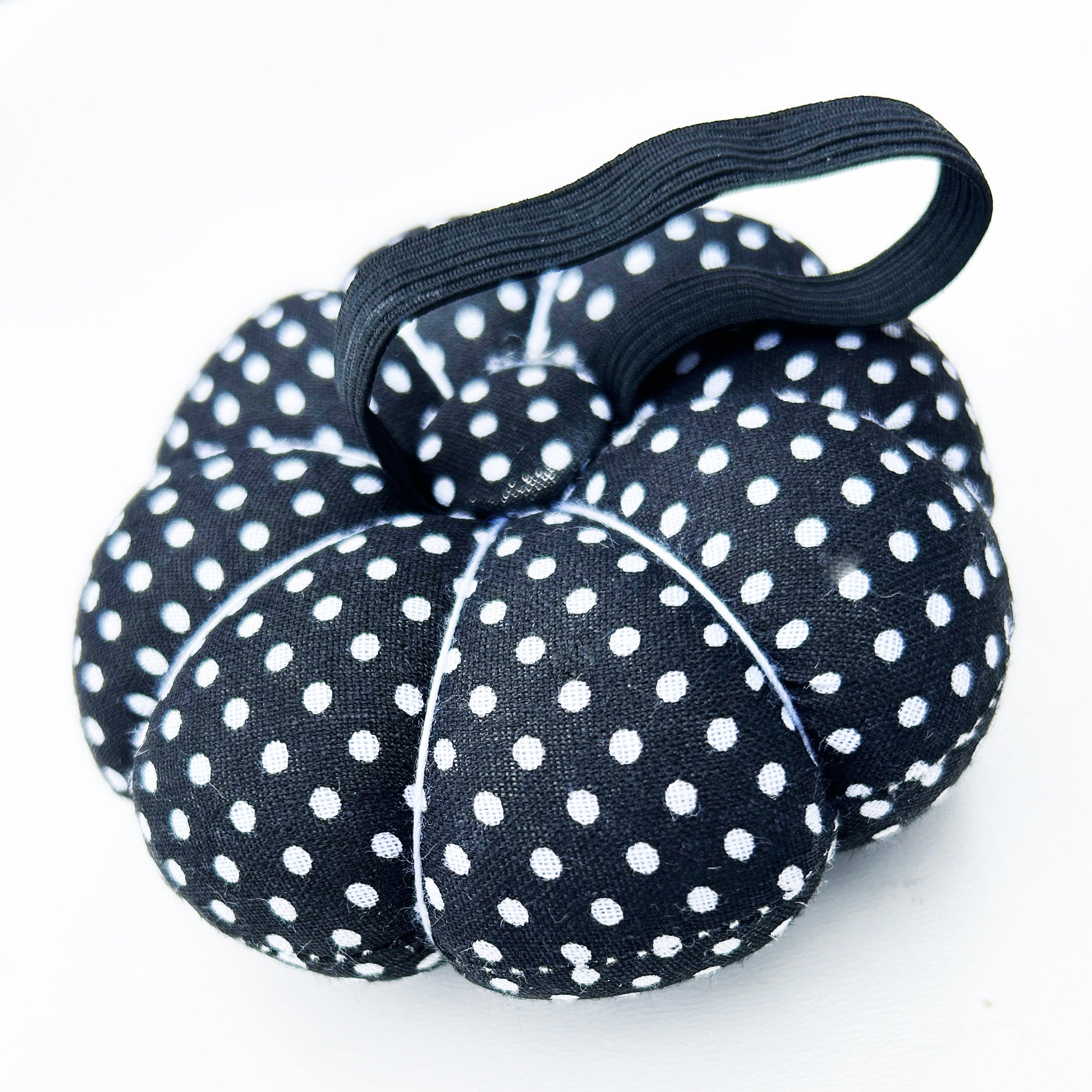 Black and white polka dot wrist pin cushion on a white background