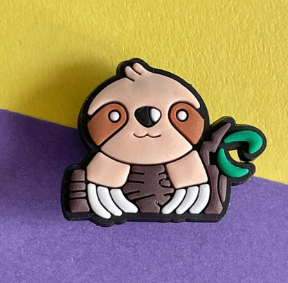 Sloth shoe charm on a log. 