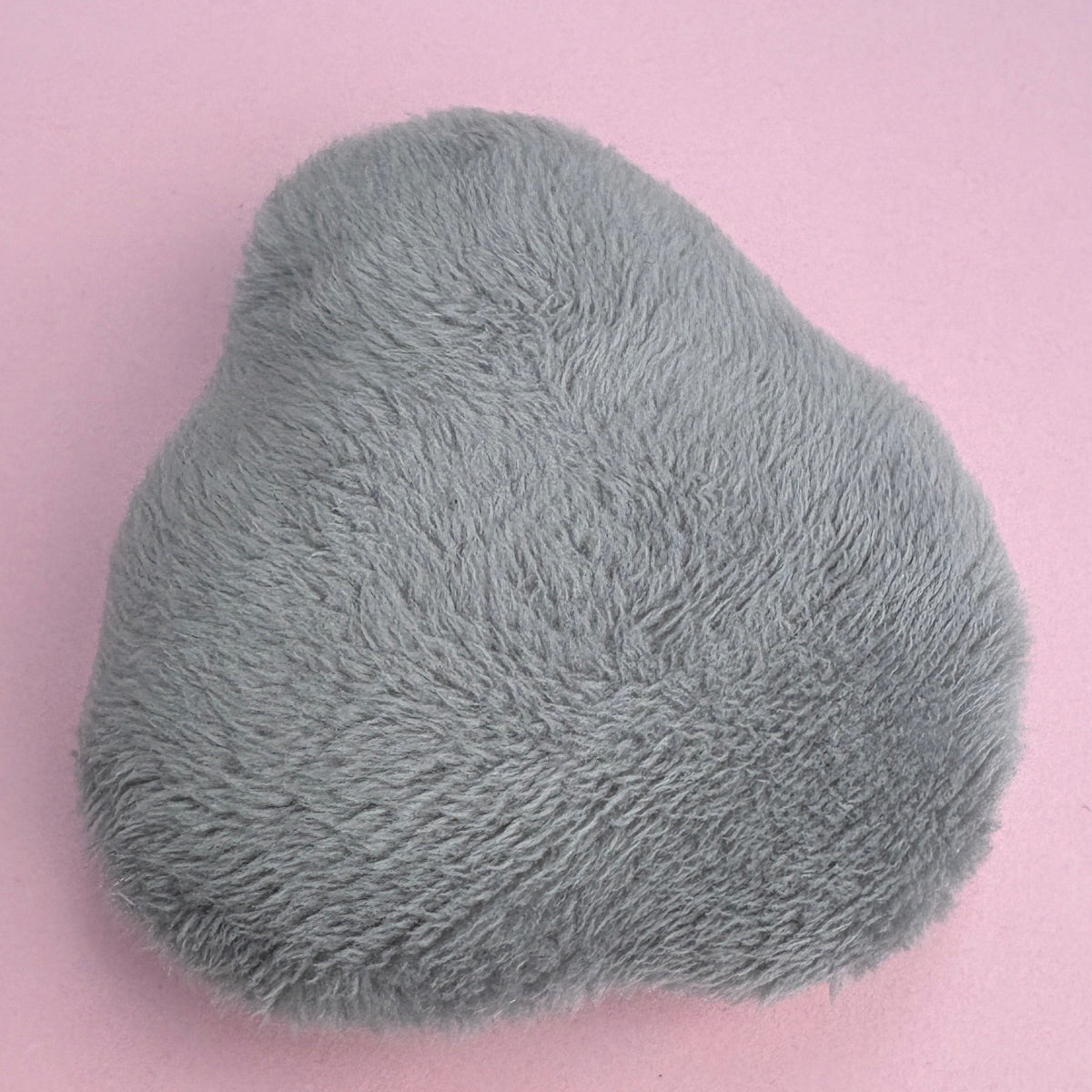 Back view of plush pigeon fidget. Plain grey fabric on a pink background.