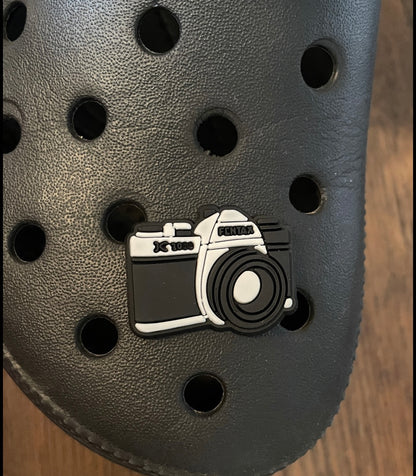 Black and white camera shoe charm on a croc shoe.