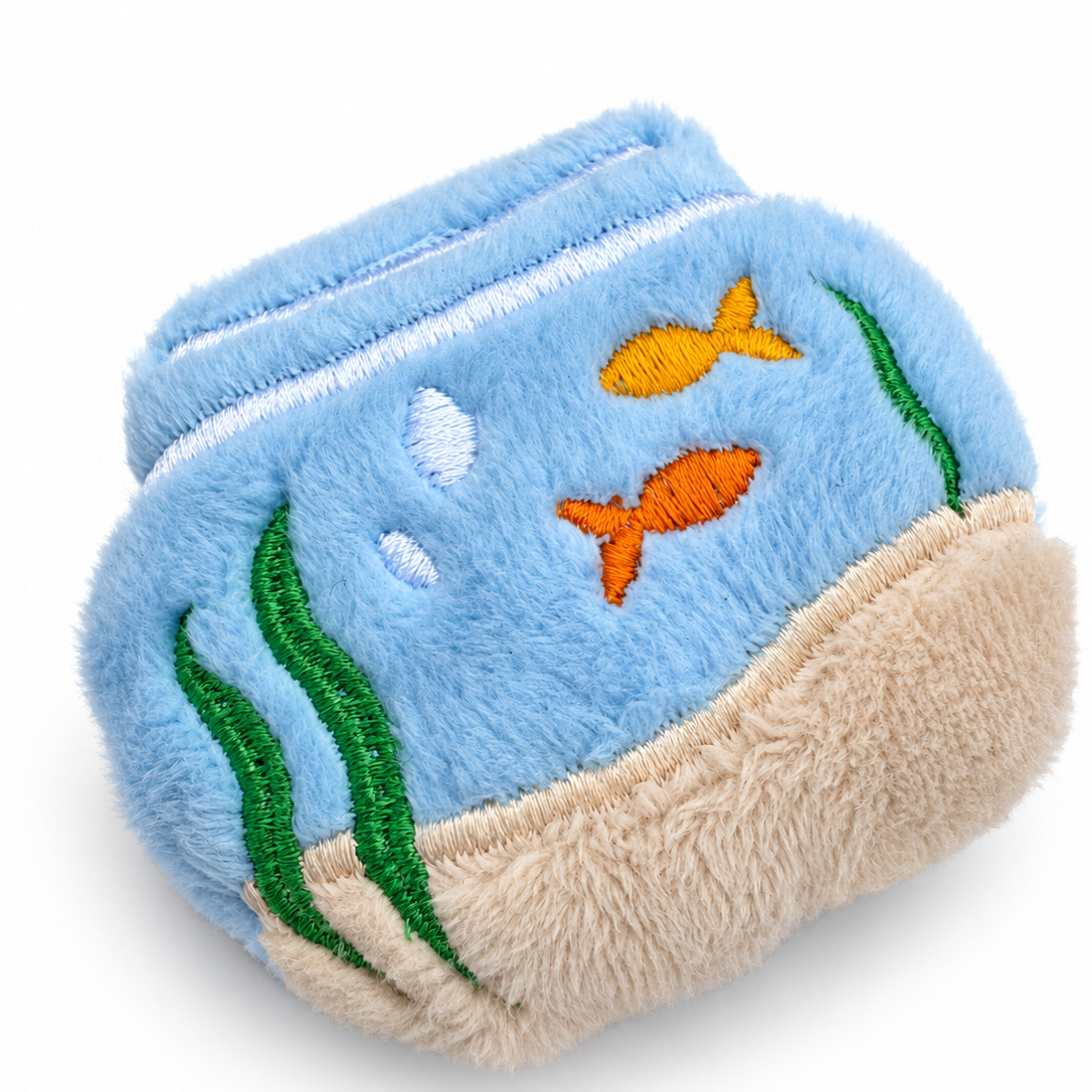 A plush fidget, soft toy shaped like an fishbowl, featuring a light blue fuzzy body with embroidered orange and yellow fish, green seaweed, white bubbles, and a sandy beige base, shown on a plain white background.