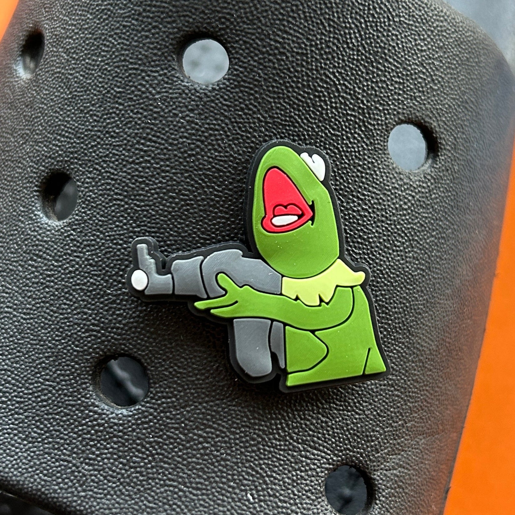 Frog holding a machine gun. Green famous puppet frog. Modelled on a croc sandle.