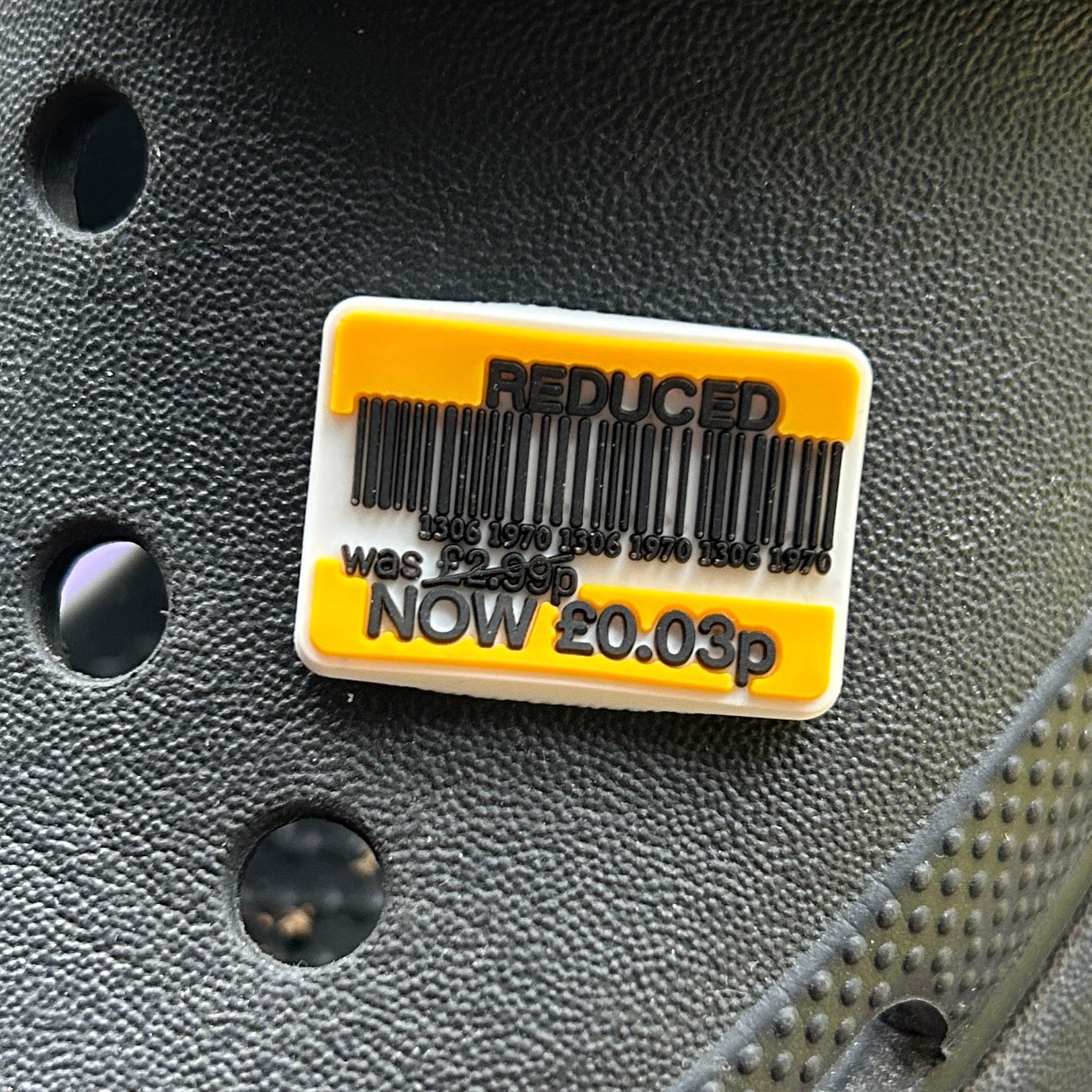 Supermarket Reduced Sticker croc like shoe charm. Show on a black croc shoe. Charm is yellow, black and white. 