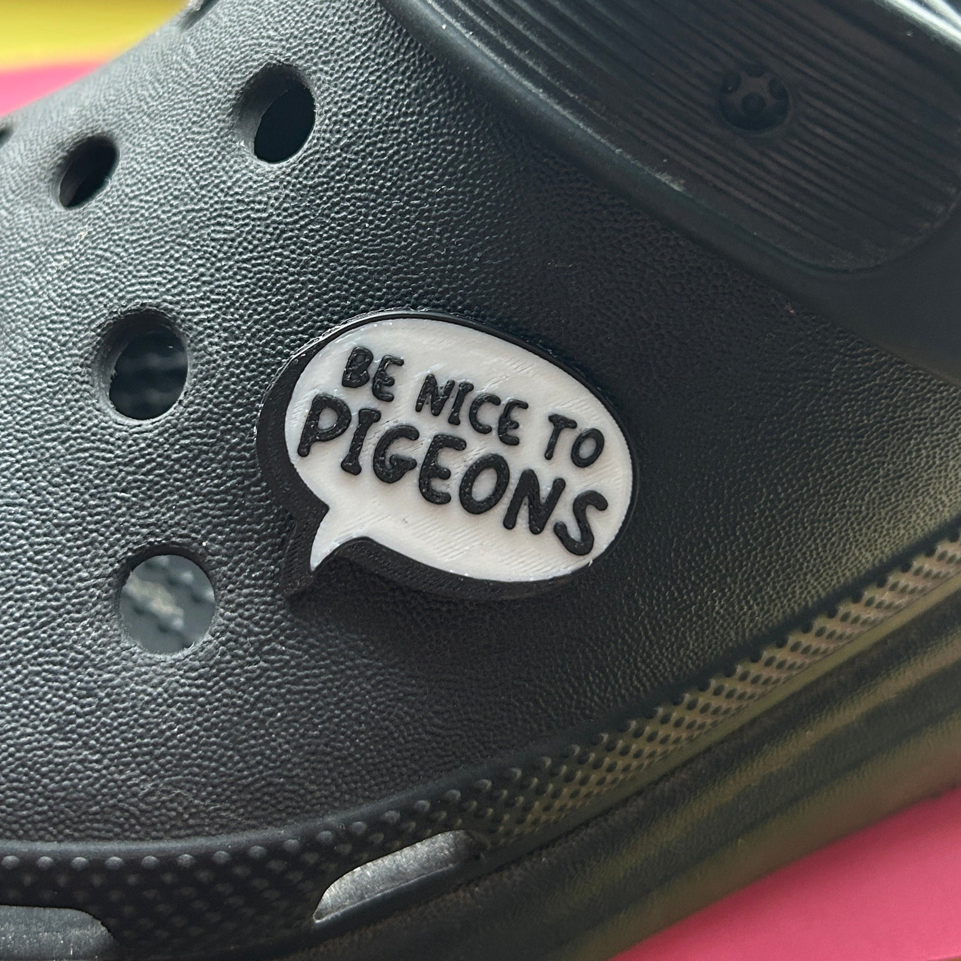 Handmade 3D Printed Be Nice To Pigeons croc like shoe charm. Shown on a black croc shoe. 