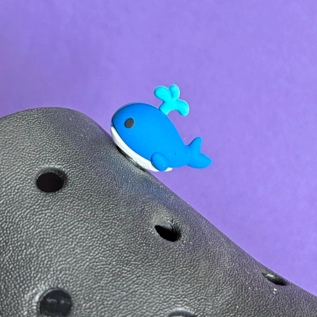 3D Whale croc like shoe charm squirting water. Shown on a black croc shoe. 