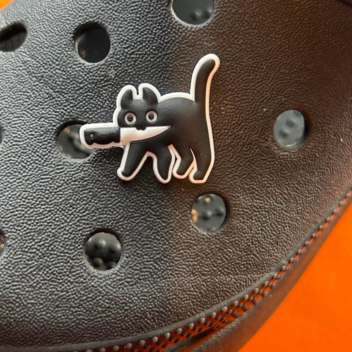 Black and white murder cat croc like shoe charm. Shown on a black croc shoe. 