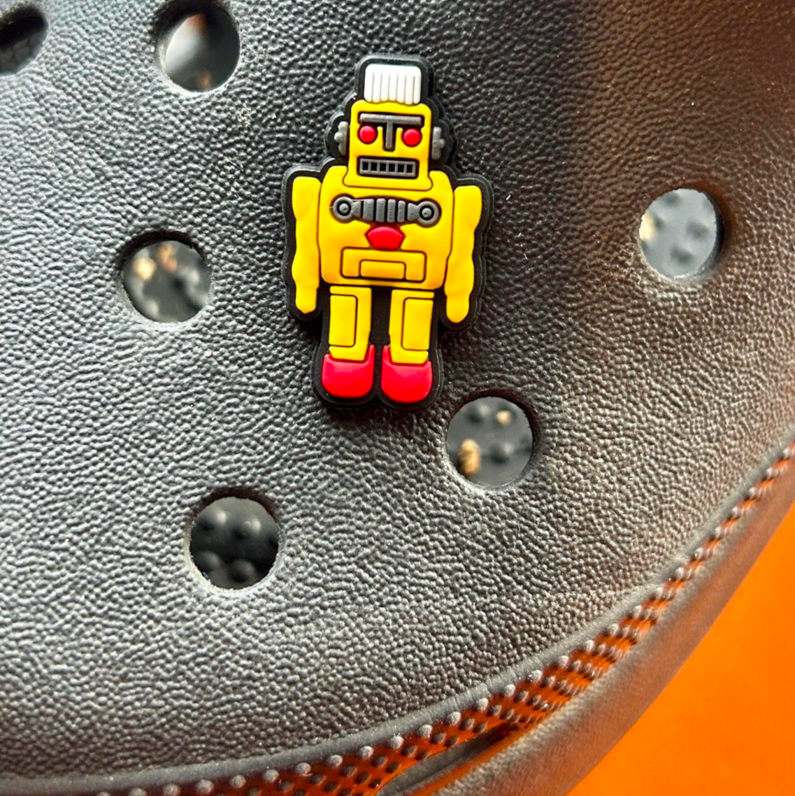 Yellow Robot croc like shoe charm. Shown on a black croc shoe. 