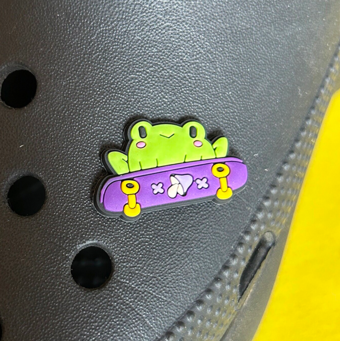 Skateboarding Frog croc like shoe charm. Shown on a black croc shoe. 