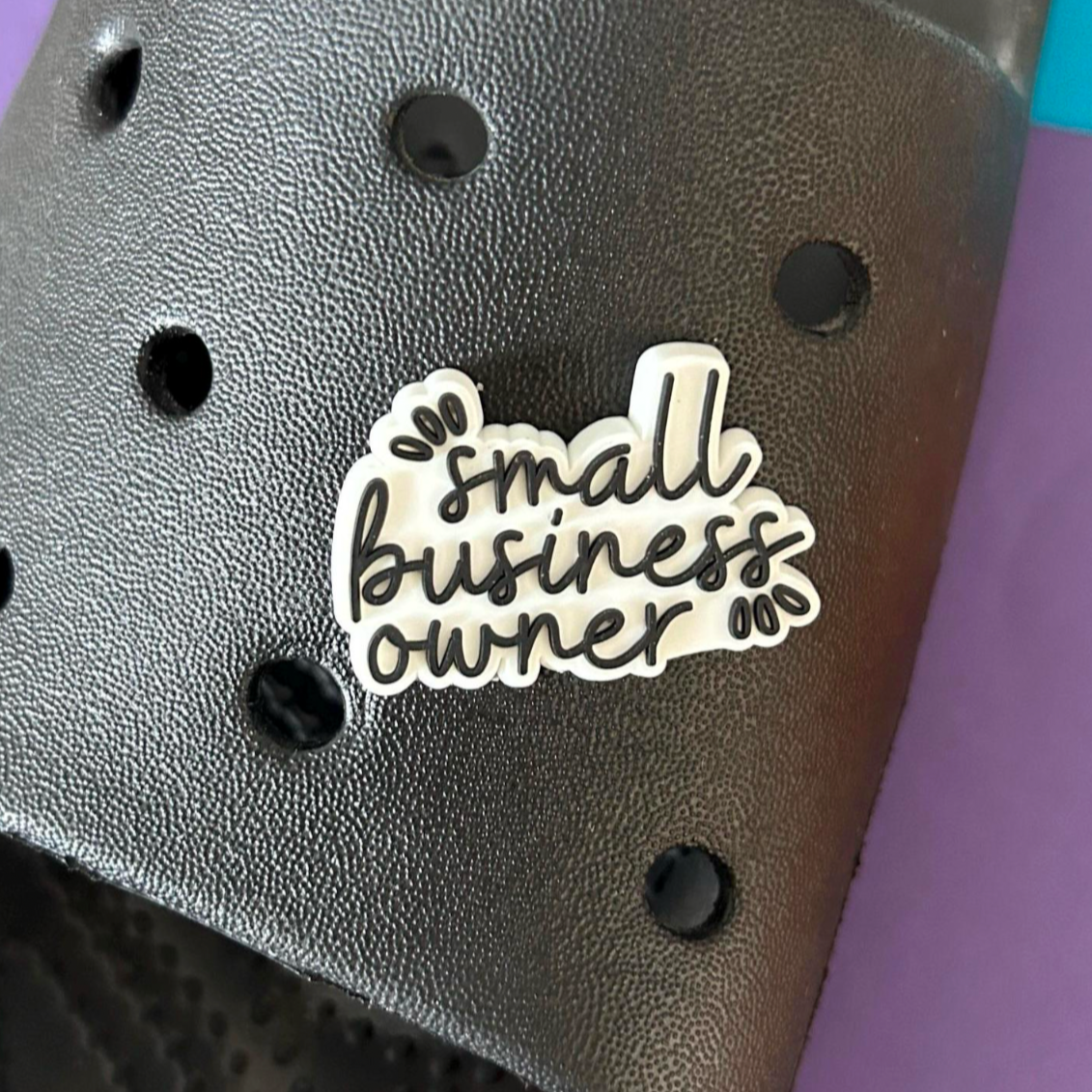 Small business owner slogan croc like shoe charm. Shown on a black croc shoe. 