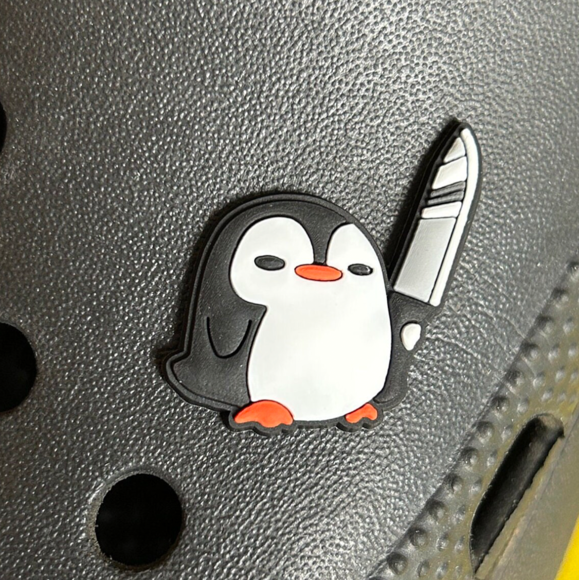 Stabby Penguin croc like shoe charm. Shown on a black croc shoe. 